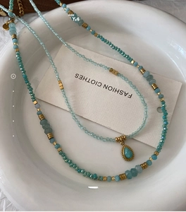 Macro detail of natural blue amazonite beaded necklace with teardrop pendant in ceramic tray