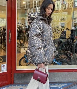 Streetstyle-Aufnahme einer Daunenjacke mit Leopardenmuster und einer roten Handtasche