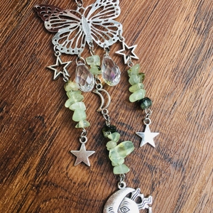 Detail of silver butterfly suncatcher with star, moon face charms and green stone