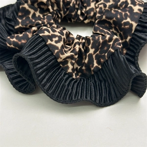 Macro shot of double-layered leopard print scrunchie with pleated black fabric edges