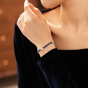 Macro detail of silver bracelet featuring blue emerald-cut stones and white flower crystals
