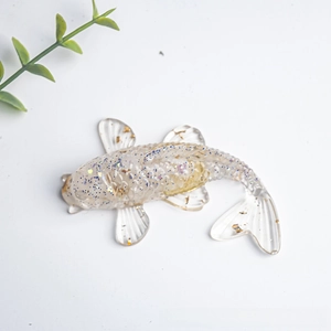 Macro view of crystal fish figurine with gold flakes and purple glitter accents