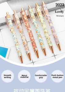 Detailed view of floral metal ballpoint pens with rose gold accents on a grid background