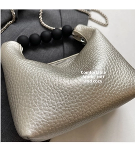 Detail of silver pebble grain leather handbag with matte black bead handle and chain