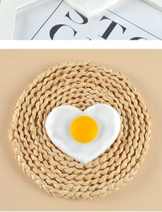 Macro shot of heart-shaped fried egg pendant on a woven mat with polished finish