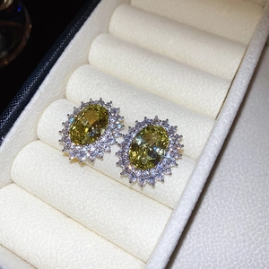 Detail view of yellow oval zircon earrings with halo stones in a cream jewelry box