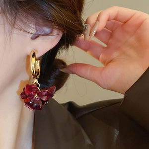 Close-up of retro gold hoop earrings with burgundy flower petals on a model