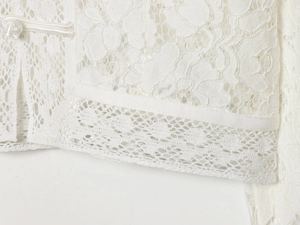 Detailed close-up of intricate lace floral texture and Chinese satin frog buttons on white shirt
