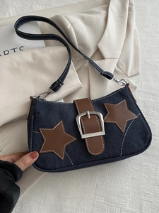 Detail of blue denim shoulder bag featuring leather stars and a silver metal buckle