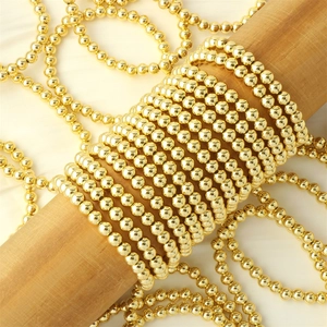 Macro shot of 18K gold plated beads layered on a wood stand with a silky background