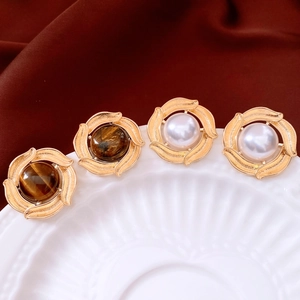Detailed view of vintage gold stud earrings with tiger eye stone and white pearl inlays