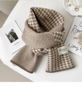 Detail of knitted houndstooth and herringbone scarf in warm brown and beige wool