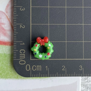 Macro shot of a tiny 1.5cm green resin Christmas wreath with a red bow and measuring ruler