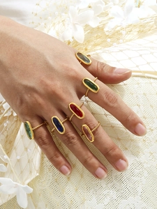 Détail de six bagues serties de pierres colorées avec anneaux torsadés dorés portées