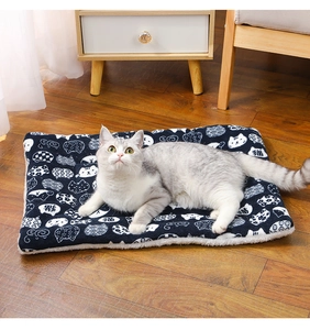 Navy blue plush pet mat with cat print used by a cat on a wooden floor in a cozy home setting