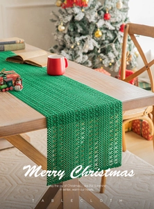 Close-up of green knitted Christmas table runner with festive holiday ornaments decoration