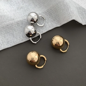 Detailed view of polished gold and silver spherical pendant earrings on a textured background