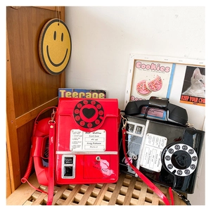 Detailed view of red and black vintage telephone crossbody bags with realistic dial pads