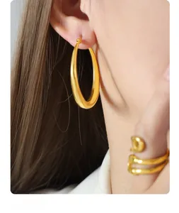 Detailed close-up of chunky gold hoop earrings and a nail-inspired wrap ring on a model