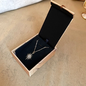 Close-up of golden sunburst pendant with black gemstone in a velvet jewelry box