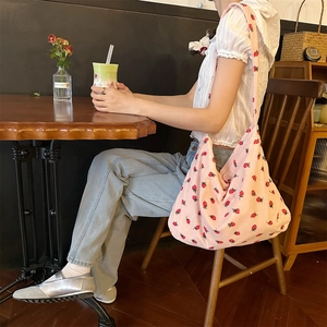 Sac cabas en velours côtelé rose avec motif fraise porté par un mannequin dans un café