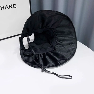 Detailed view of the smooth black satin texture and adjustable windproof strap on the sun hat