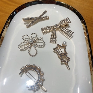 Detailed close-up of rhinestone and pearl hair clips set in a white display tray
