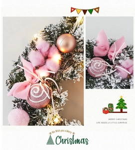 Détails d'une couronne de Noël rose avec lumières LED, boules de coton et ornements