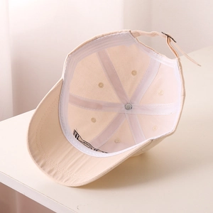 Internal view of beige kids baseball cap showing reinforced seams and adjustable metal buckle