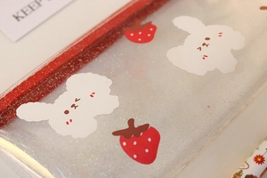 Detail of transparent glitter pencil case with cute dog and strawberry patterns