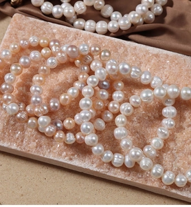 Macro shot of natural baroque freshwater pearls on stone slab with brown silk fabric background