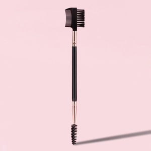 Detail of dual-ended eyebrow brush and eyelash comb with rose gold ferrule on pink background