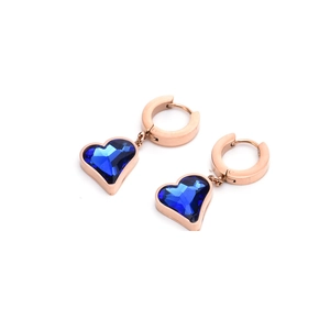 Detail view of rose gold titanium earrings featuring a deep blue heart-shaped gemstone