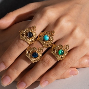 Close-up of four gold crown rings with colorful stones on a hand model