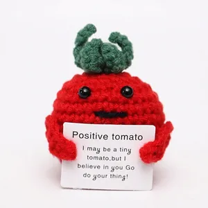 Handmade crochet positive tomato doll with green leaf holding an encouragement card