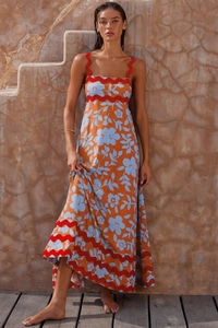 Detail of bohemian floral maxi dress with vibrant orange print and wavy red trim accents