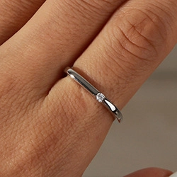 Macro shot of silver ring with minimalist small round diamond on finger detail