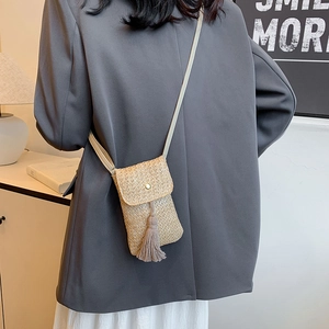 Minimalist straw woven crossbody bag with stylish tassels shown on female model