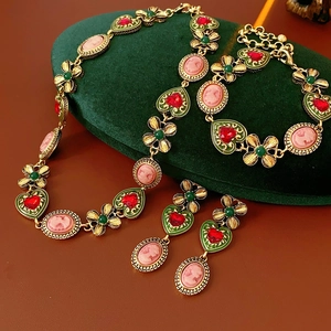 Détail de parure bijoux vintage avec camées roses et cœurs rouges sur velours vert