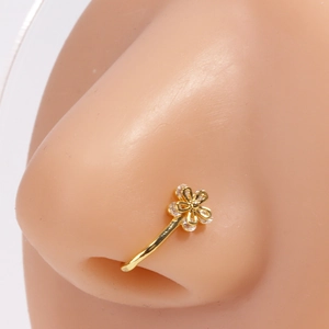 Détail d'un faux piercing nez fleur dorée avec zircon blanc sur un modèle en silicone