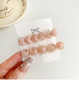 Close-up of pink marble resin heart and bead hair clips on a white display card