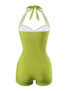 Detail of green halter neck one-piece swimsuit with white contrast piping and boyleg cut