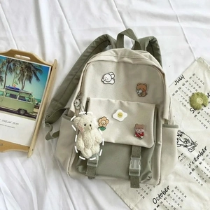 Detail of Korean-style backpack with cartoon badges and a white plush bear charm