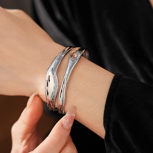 Macro shot of silver irregular lava texture cuff bracelet with dual-layer pleated design
