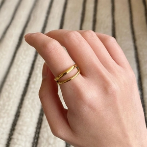 Minimalist double-layered gold ring on index finger with cozy knit background detail