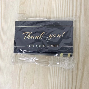 Macro detail of dark blue thank you cards with gold foil lettering on a wood surface