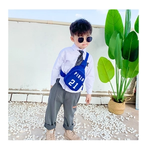 Blue canvas kids chest bag with Pirlo 21 print shown on a child model in a garden