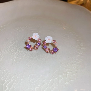 Detail of flower wreath earrings with purple zircons and white resin petals