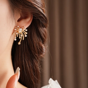 Close-up of 18K gold-plated firework earring with pearls and crystals on female ear