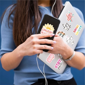 Holographic motivational stickers on laptop and phone with colorful aesthetic slogans